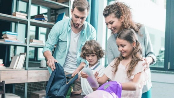 Pais ajudando o filho a organizar os materiais escolares para retomar a rotina escolar após as férias com tranquilidade e motivação.